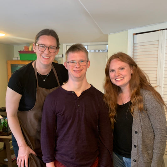 Three people stand together smiling.