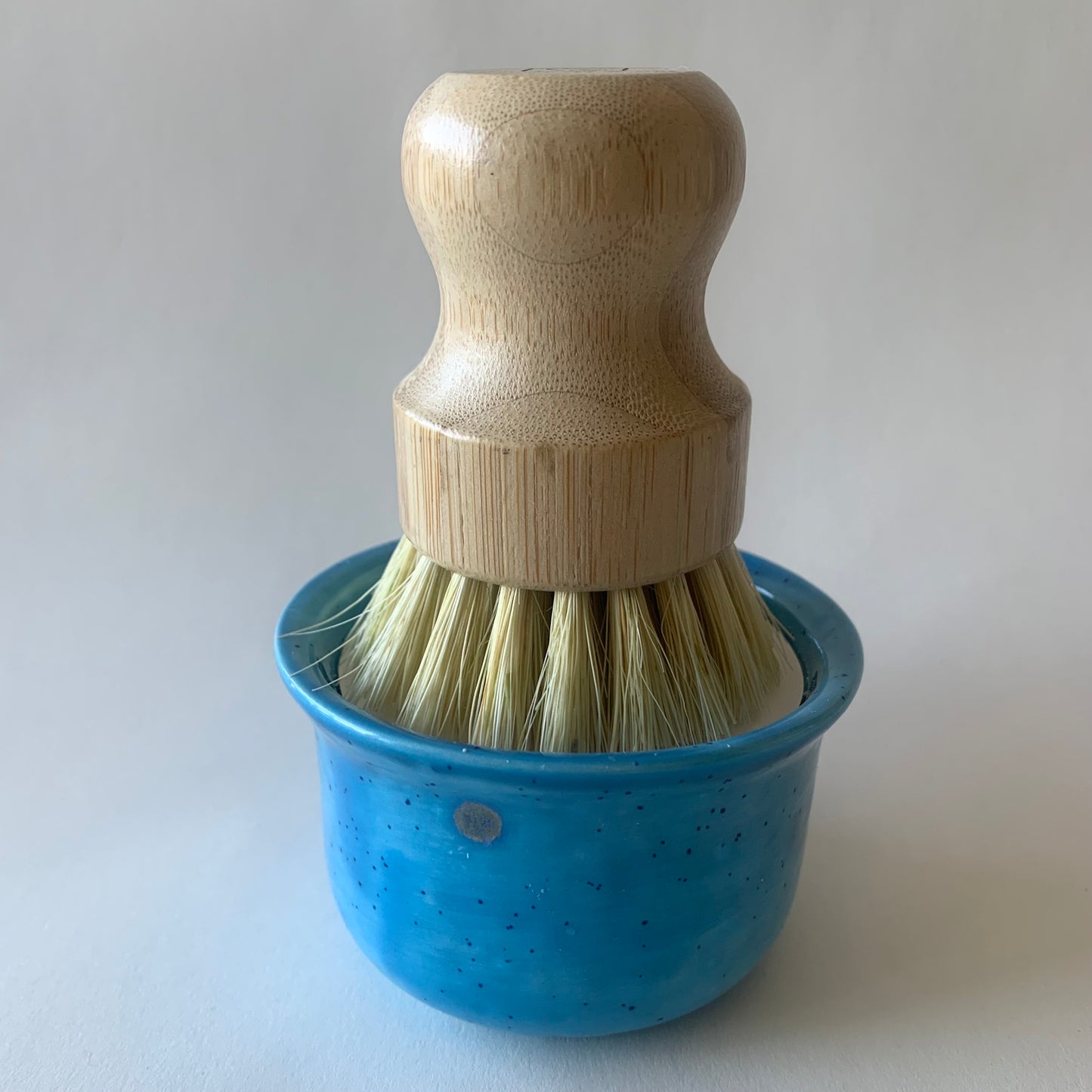 blue ramekin with wood dish brush sitting on soap