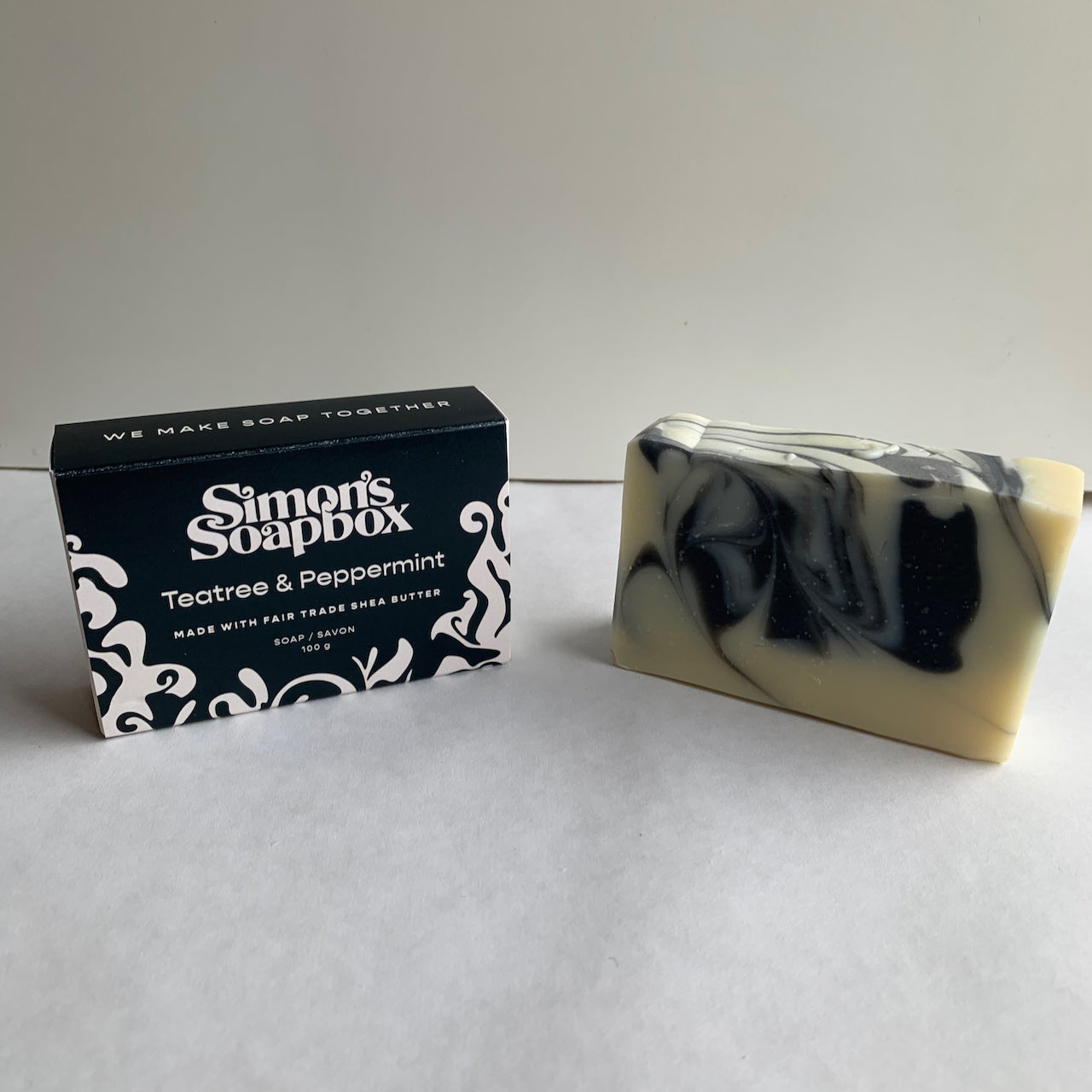 two bars of soap, one in a black and white package and one unwrapped with a black and grey swirl