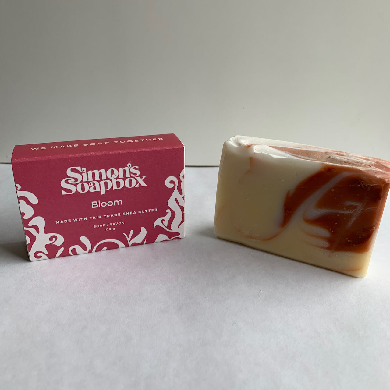 two bars of soap, one with a coral swirl and one a pink package