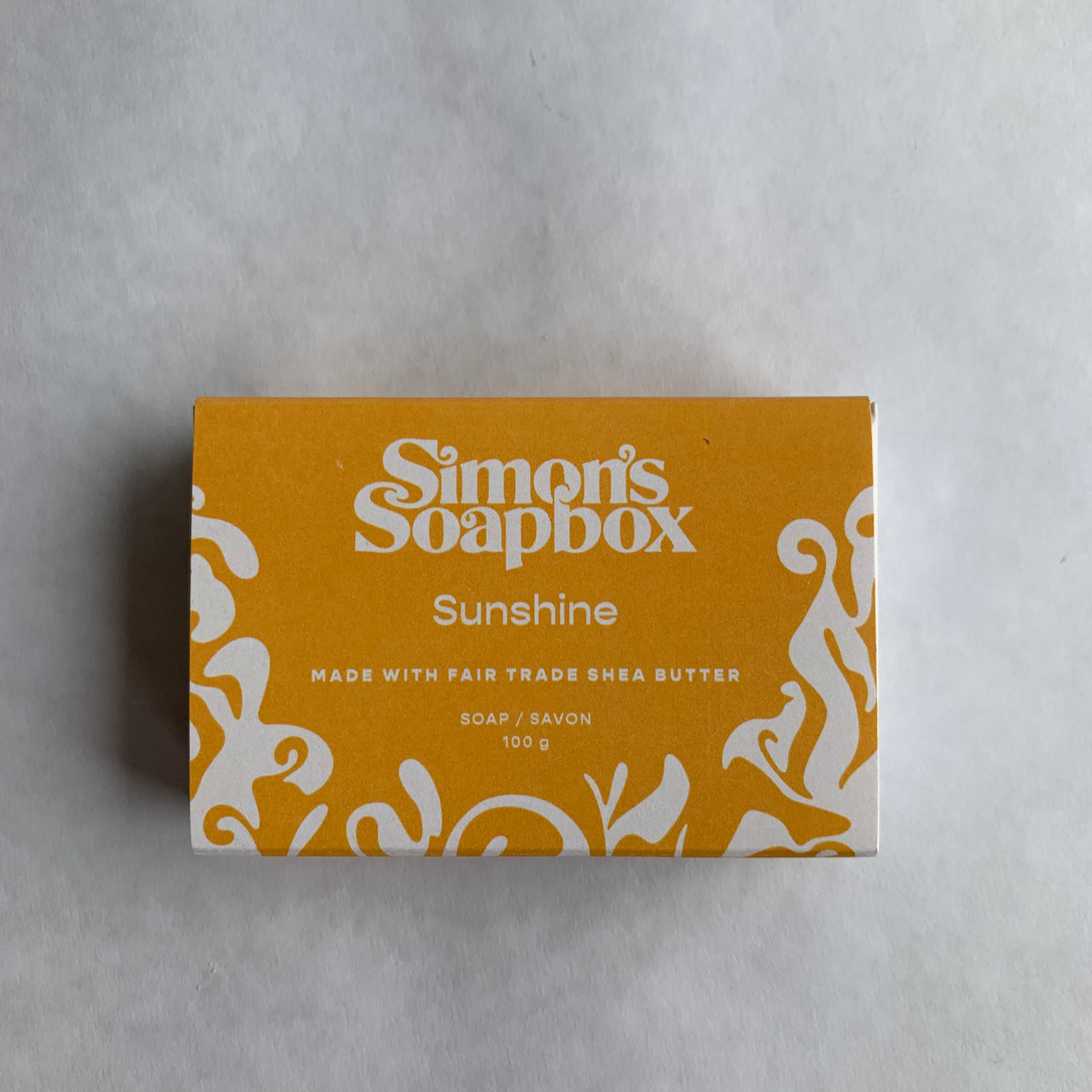 yellow rectangle package with swirl design and the words Simon's Soapbox Sunshine made with fair trade shea butter soap/savon 100 g