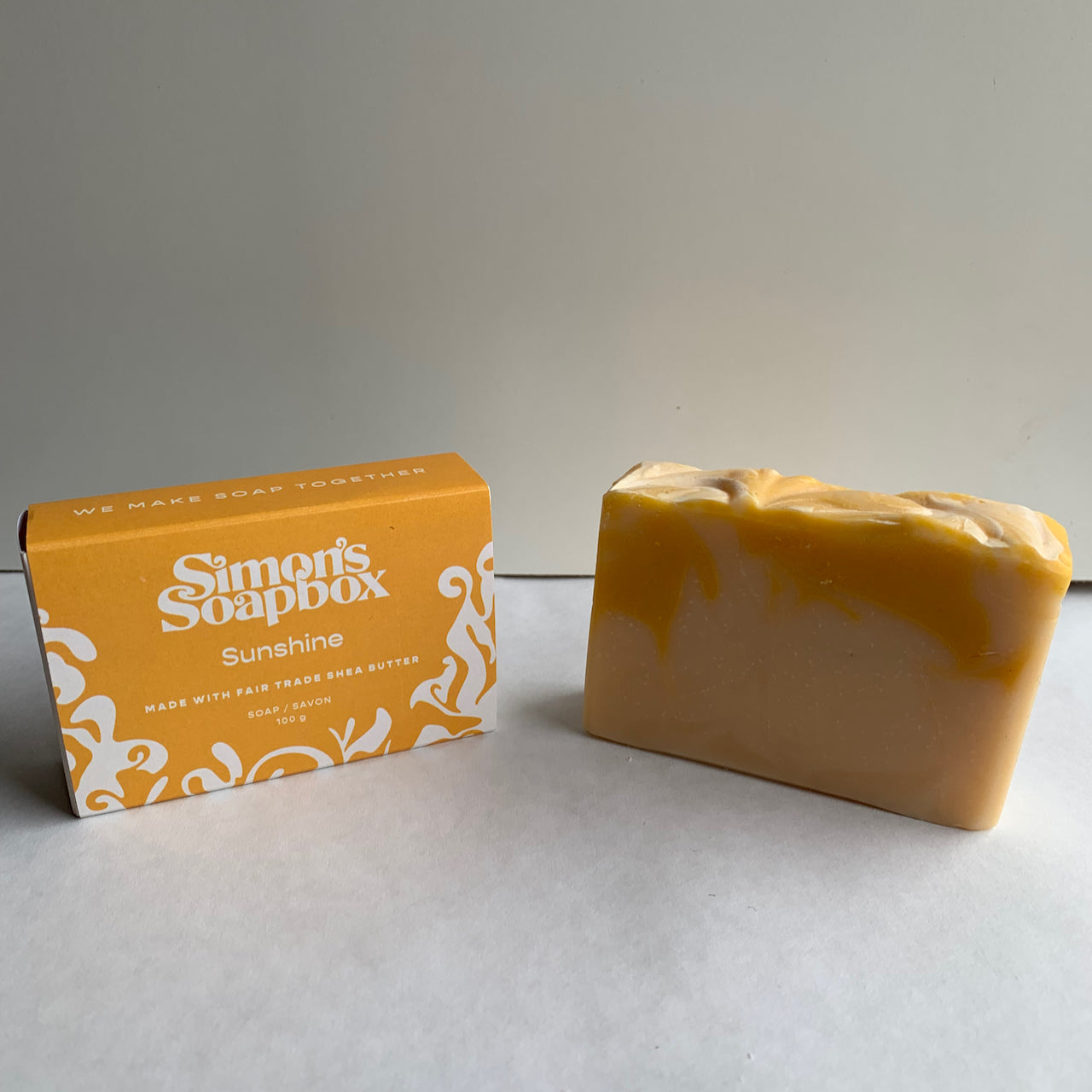 two bars of soap, one in a package and one unwrapped with a yellow swirl in it
