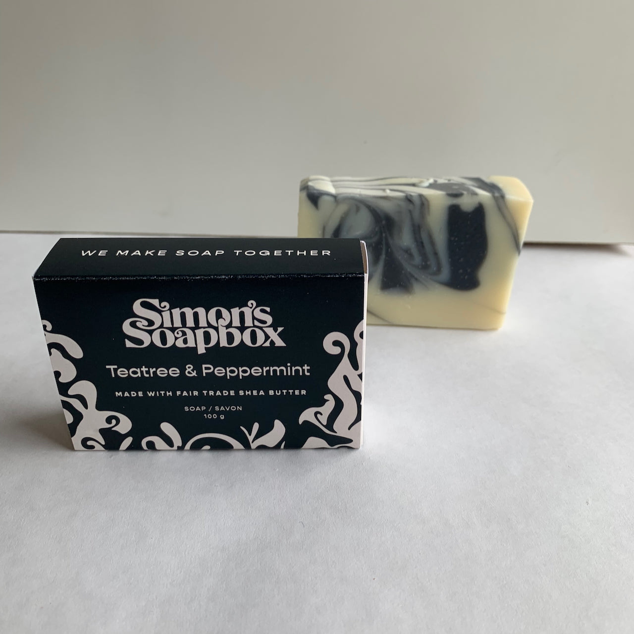 two bars of soap, one unwrapped and one in a package that reads we make soap together on the side
