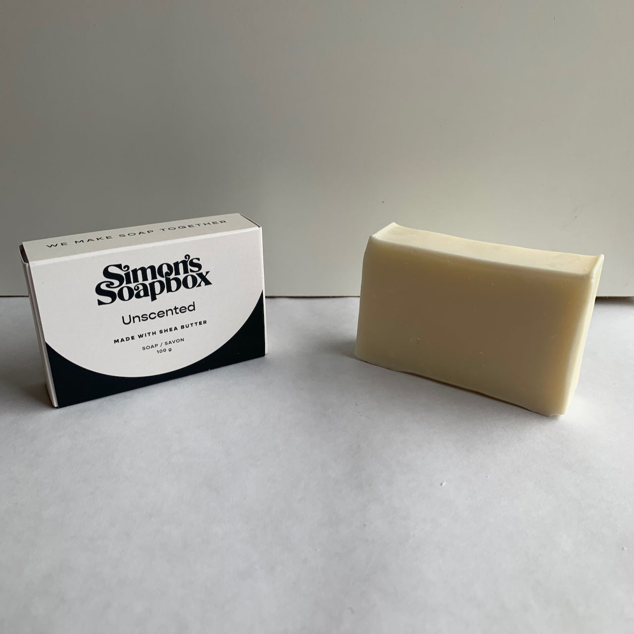 two bars of soap, one in a package, one cream bar unwrapped