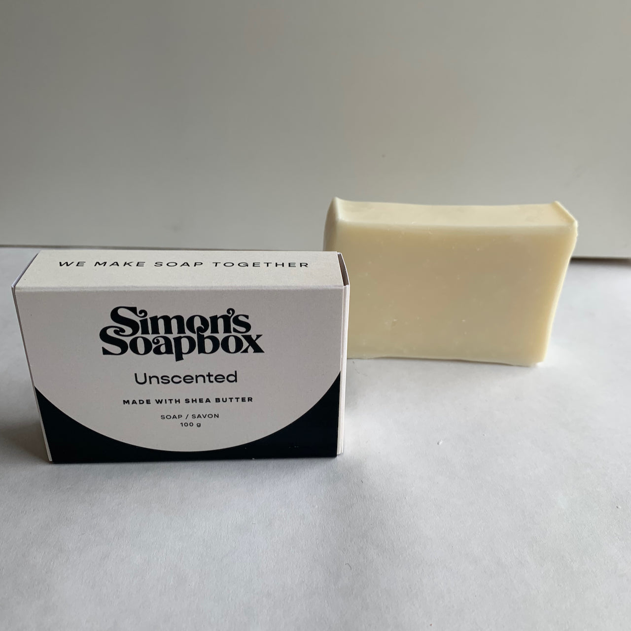 two bars of soap, one unwrapped, one in a package that reads we make soap together on the side